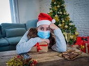 Women with santa hat resting on a present looking depressed. 